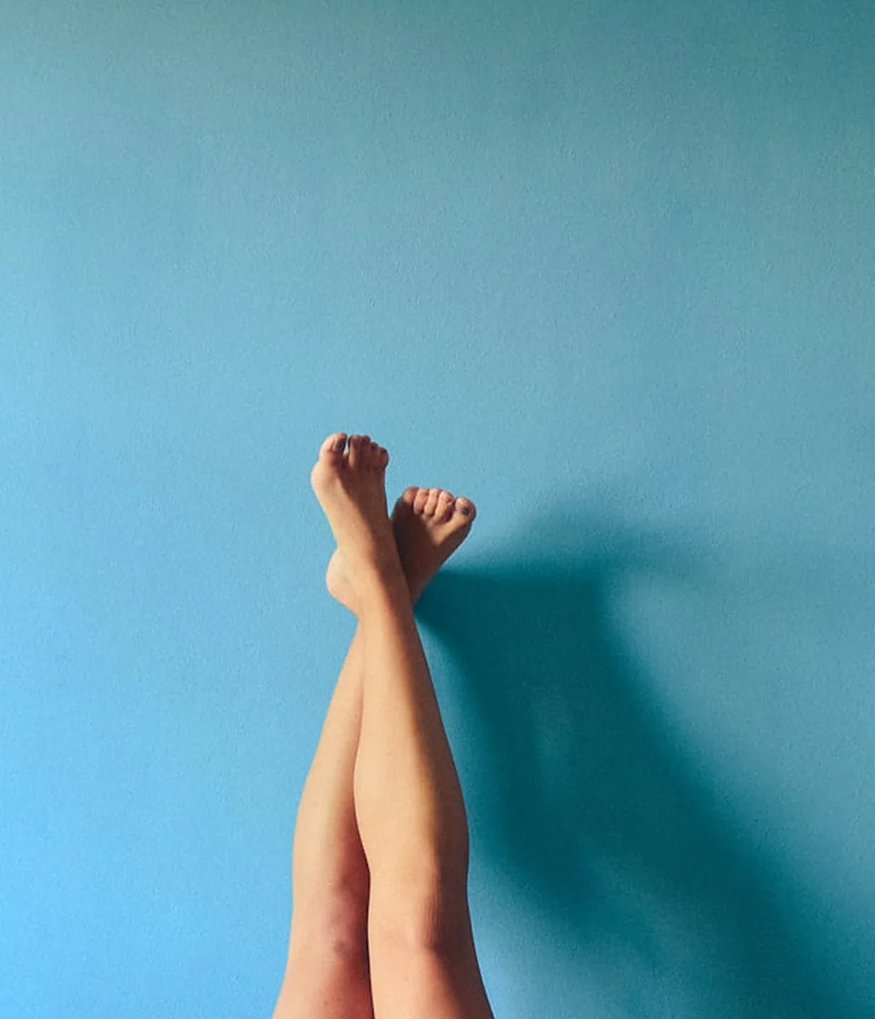 Healthy, cared-for feet resting against a blue wall